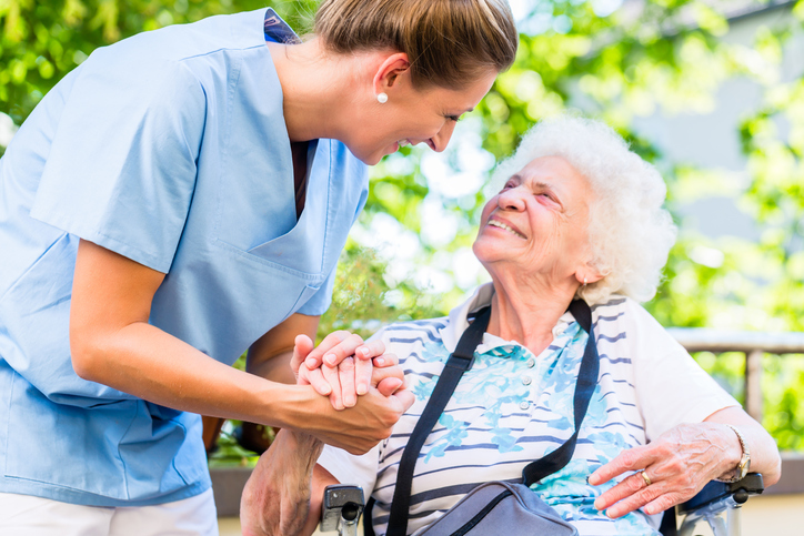 elderly-woman-outside-with-caregiver-in-blue-scrub-top